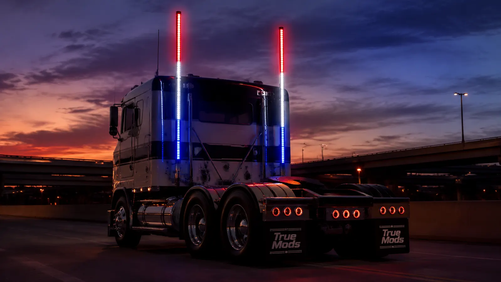 Hand holding a True Mods 4ft LED whip light, illuminated RGB strip showing red, white, and blue colors against a dark truck cab background