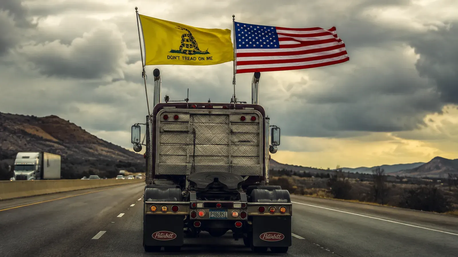 Anley Gadsden flag flying hard in wind beside an American flag on a semi truck, both flags extended full