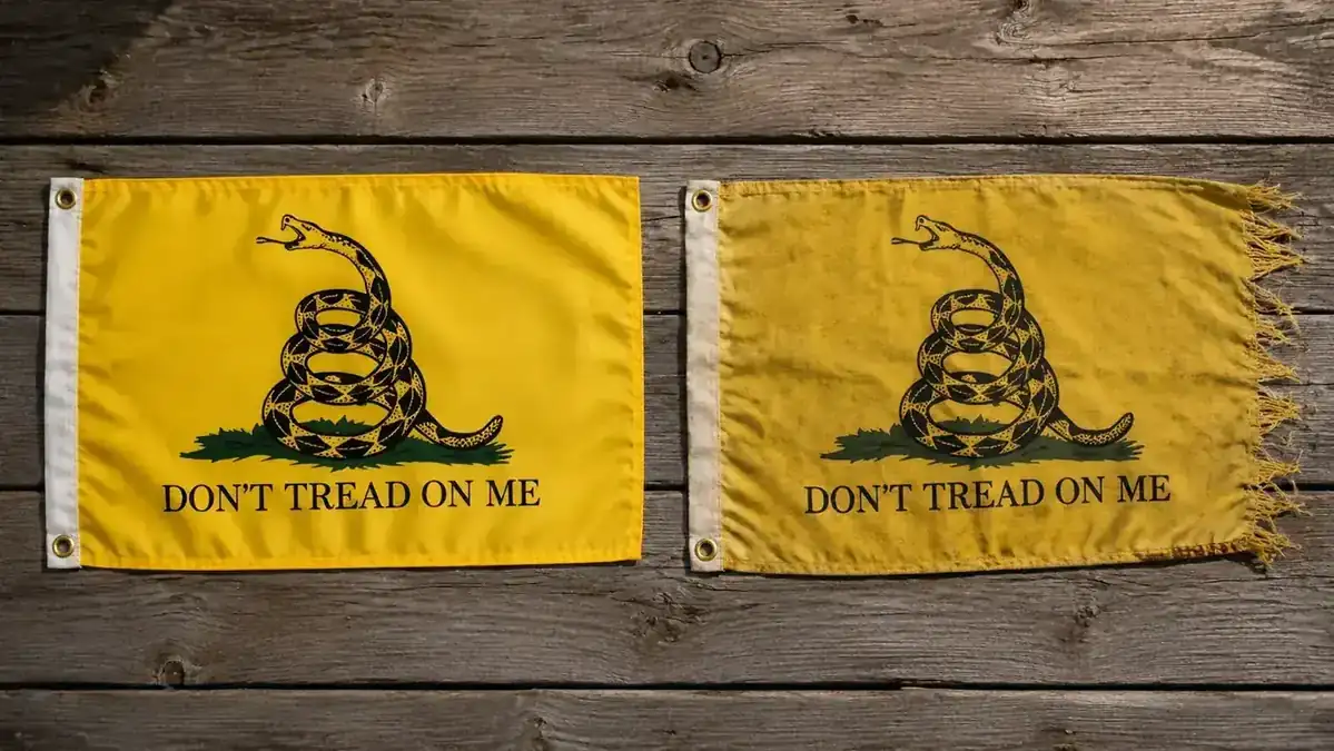 Two Gadsden flags side by side after outdoor use showing color and edge condition difference