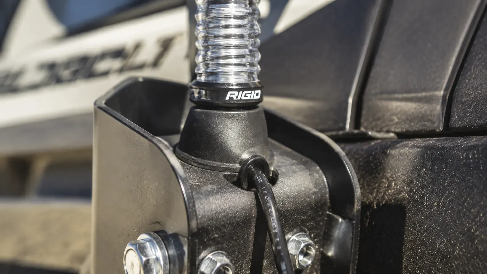Close-up of the LED whip base connection point on a truck mount bracket, with rubber seal visible around the wire entry, showing waterproof design