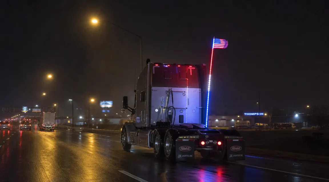True Mods LED whip USA flag lit up at night on interstate, bright RGB glow visible from 300 feet away